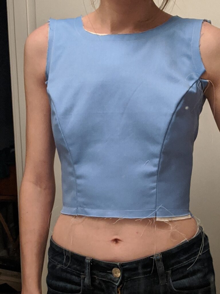 A closeup from the front of Amy's torso showing the fit of the blue mock-up of her wedding dress bodice.
