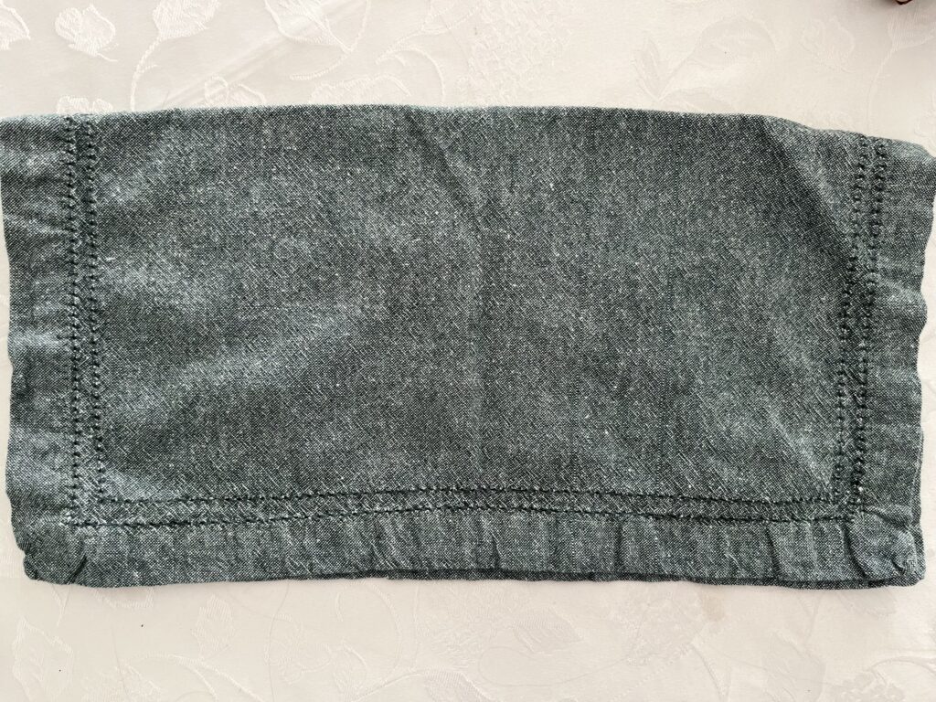 A green napkin folded in half lengthwise.