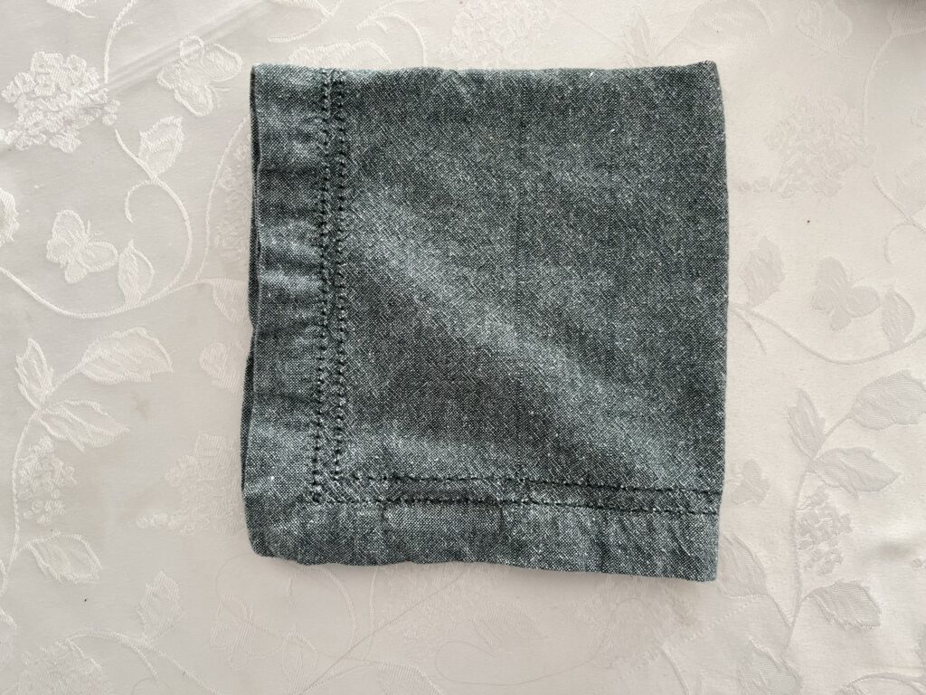 A green napkin folded in quarters.