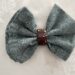 A green napkin has been partly fed through a brown napkin ring and shaped into a bow.