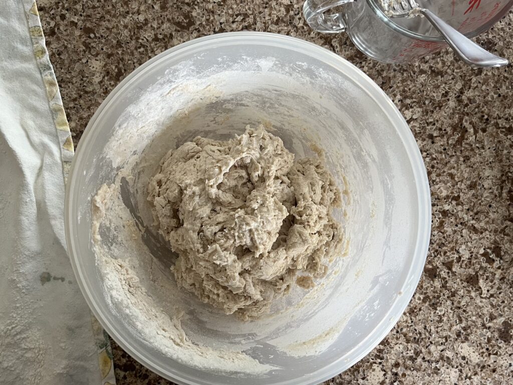 The mixed dough sits in a bowl, with an empty measuring cup nearby.