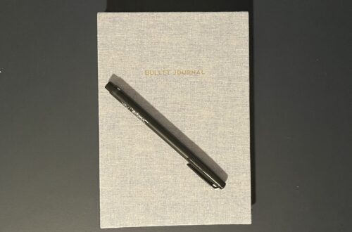 A closed notebook labeled "Bullet Journal" with a felt tip pen sitting on top.