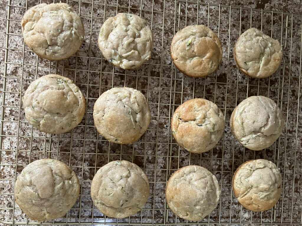 Cooked zucchini muffins, lightly browned, on a cooling rack.