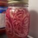 A close up of a jar of pickled red onions.