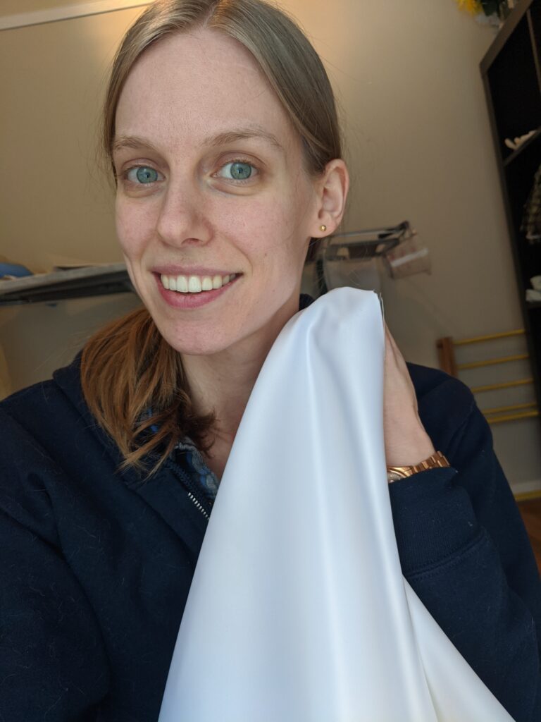 Selfie of Amy holding up her wedding dress fabric to her face to see how it looks