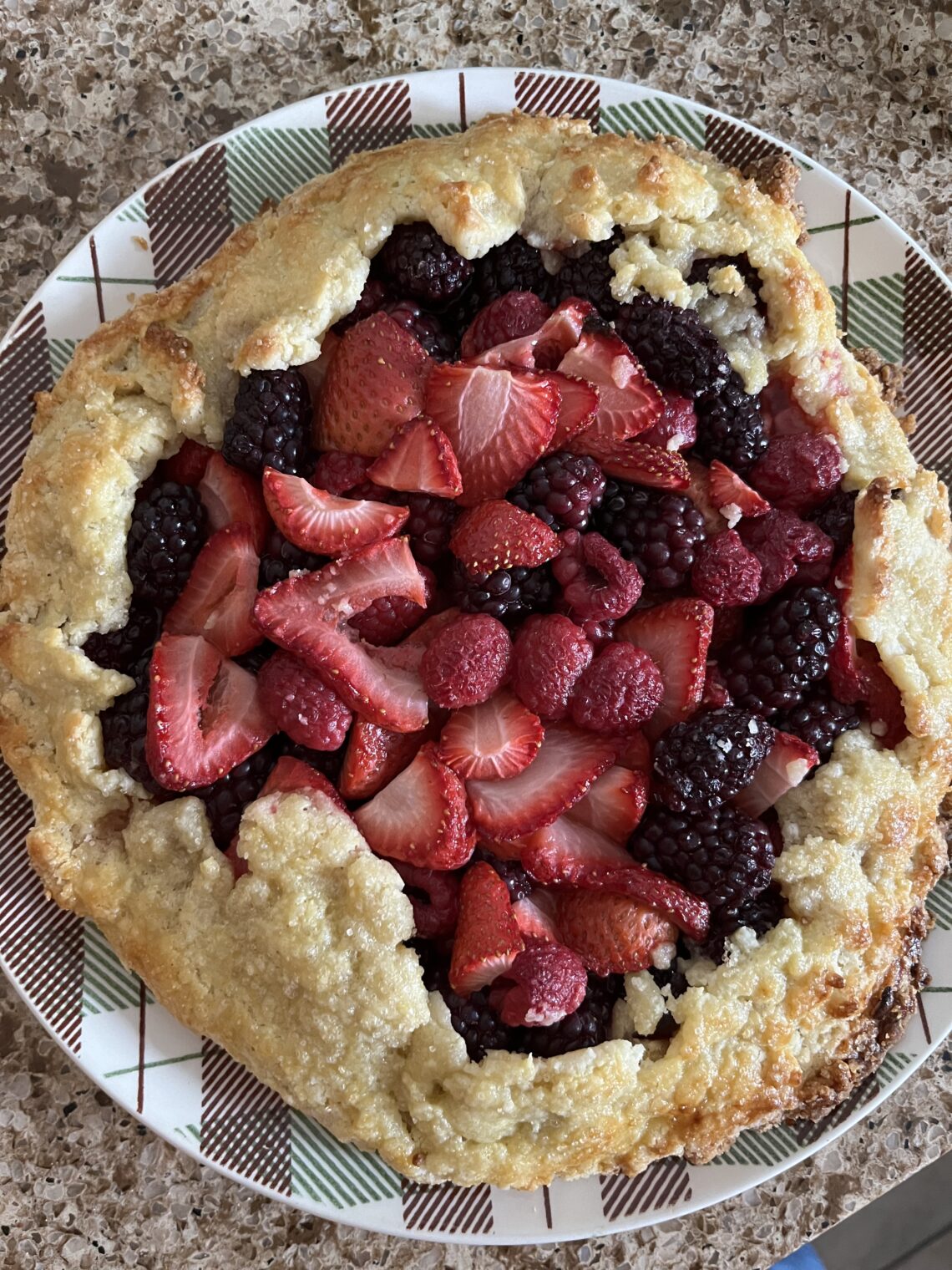 a roughly shaped mixed berry galette (a type of pie), sitting on a serving plate.